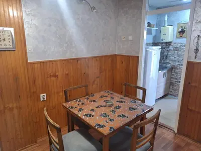 a table and chairs in a kitchen with a table and a refrigerator at apartman Milica in Ruma
