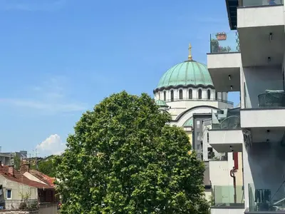 a tree in front of a building with a dome at Apartment Maria Belgrade Residence in Vračar (historical)