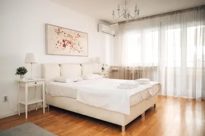a white bedroom with a white bed and a chandelier at Crown Central three bedroom Apartment in Belgrade