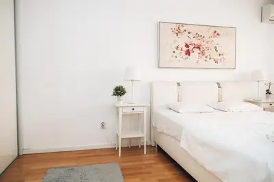a white bedroom with a bed and a picture on the wall at Crown Central three bedroom Apartment in Belgrade