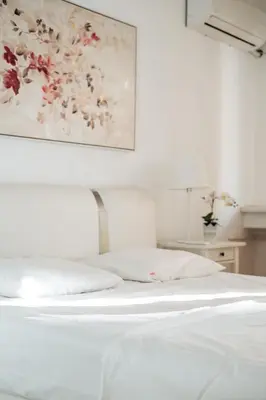 a bedroom with a white bed with a painting on the wall at Crown Central three bedroom Apartment in Belgrade