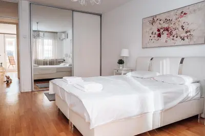 a white bedroom with a large bed and a mirror at Crown Central three bedroom Apartment in Belgrade