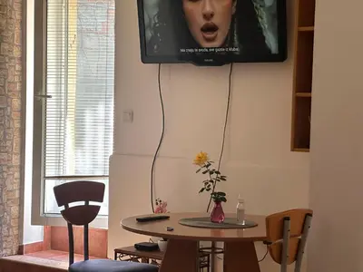 a tv hanging on a wall above a table at Apartment GreenTerrace next to TC BIG FASHION Mall in Karaburma