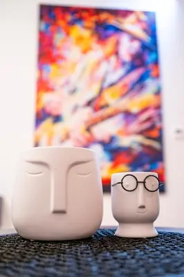 two toy heads with glasses next to a cup at Andrej Lux in Jajinci
