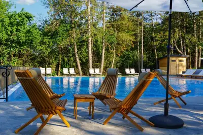 two chairs and an umbrella next to a swimming pool at Espacio Resort - Pool & Spa in Novi Vladimirovac