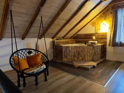 a room with a swinging chair and a tub at NaVisu avlija in Kruševica