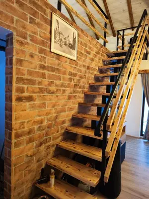 a brick wall with a wooden staircase in a room at NaVisu avlija in Kruševica