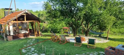 a yard with chairs and a hammock and a house at NaVisu avlija in Kruševica