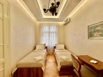 two beds in a room with a table and a window at Djuras residence in the center of Belgrade in Belgrade