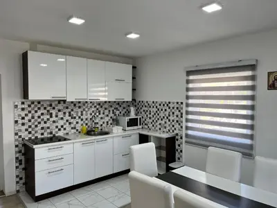 a kitchen with white cabinets and a table and chairs at Čajića avlija in Obrenovac