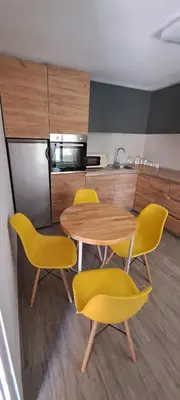 a kitchen with a wooden table and yellow chairs at Vila Felicita in Sremski Karlovci