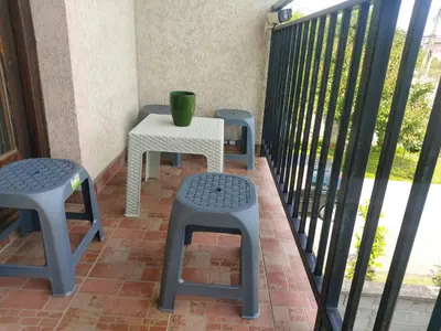 a table and two stools on a balcony with a green cup at LB boka 216 in Mali Mokri Lug