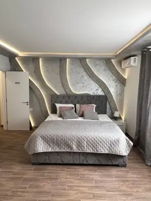 a bedroom with a large bed with a painting on the wall at S class apartment in Novi Grad