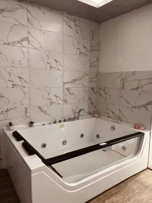 a white bath tub in a bathroom with marble walls at S class apartment in Novi Grad