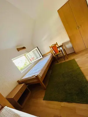 a small room with a bed and a green rug at Rooms for rent 