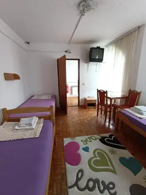 a room with two beds and a table with a tv at Rooms for rent 