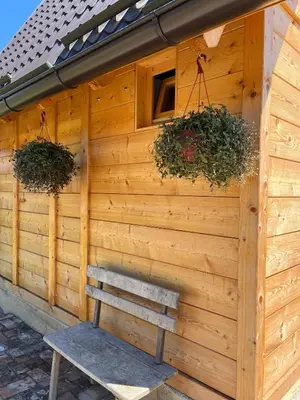 a wooden building with two potted plants and a bench at Kućica naša bajka in Kupinovo