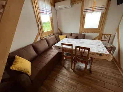 a living room with a couch and a table and chairs at Kućica naša bajka in Kupinovo