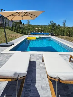 a pool with two beds and an umbrella at K42 pool house in Vlasi