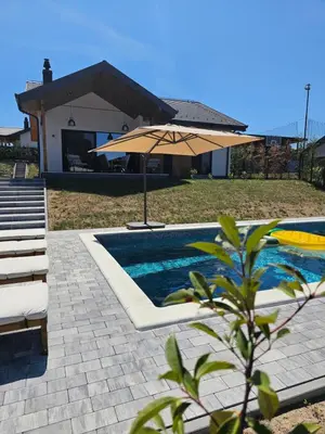 a swimming pool with an umbrella next to a house at K42 pool house in Vlasi