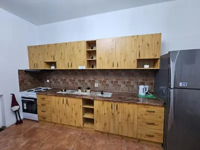 a kitchen with wooden cabinets and a refrigerator at Kalina Apartman in Belgrade