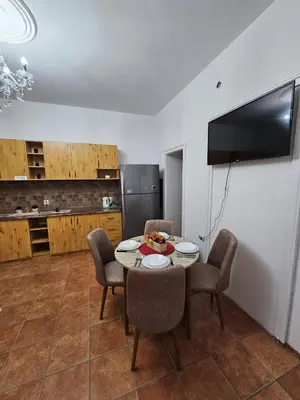 a dining room with a table and chairs and a kitchen at Kalina Apartman in Belgrade