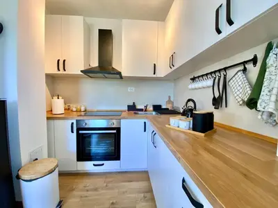 a kitchen with white cabinets and a wooden floor at Košutica Vila in Koraćica