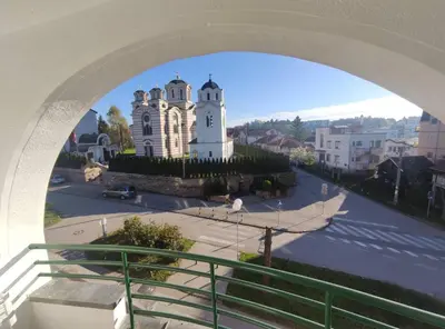 a view of a church from an arch of a building at Apartman Osmeha in Mladenovac