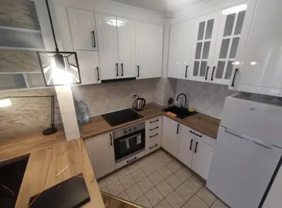 a kitchen with white cabinets and a stove top oven at Apartman Osmeha in Mladenovac