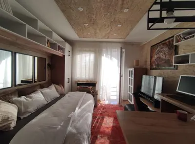 a bedroom with a bed and a desk and a television at Apartman Osmeha in Mladenovac