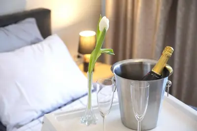 a bottle of champagne and a flower in a bucket on a table at Apartment BW Maria Belgrade in Sajmište