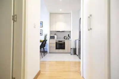 a kitchen with white cabinets and a wooden floor at Apartment BW Maria Belgrade in Sajmište
