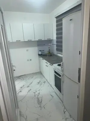 a kitchen with white cabinets and a white refrigerator at STAN Beograd in Belgrade