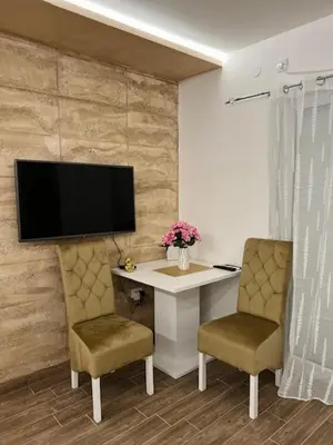 a desk with two chairs and a television on a wall at 5 star apartment in Novi Grad