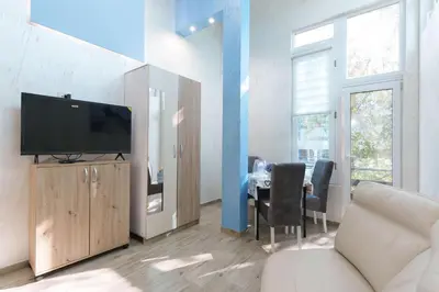 a living room with a television and a table with chairs at Step rooms apt spa in Belgrade