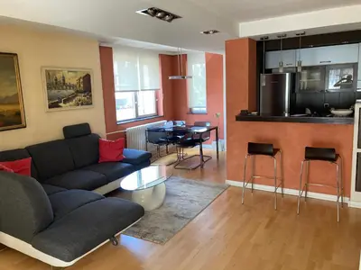 a living room with a couch and a table and a kitchen at Waterfront with free parking in Sajmište