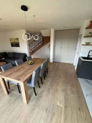 a dining room and living room with a wooden table and chairs at Panorama Kosmaj in Sopot