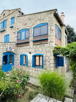 a stone building with blue doors and windows at Stone villa in Fruška gora in Irig