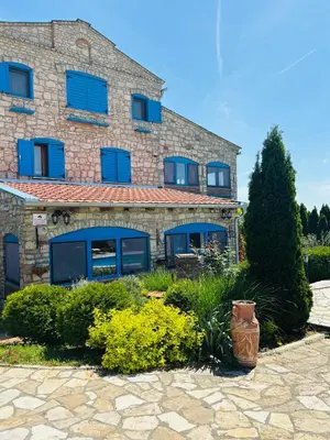 a stone building with blue shutters on it at Stone villa in Fruška gora in Irig