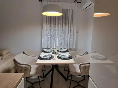 a white dining room table with chairs and a light at Apartmani Kolaković in Arandjelovac