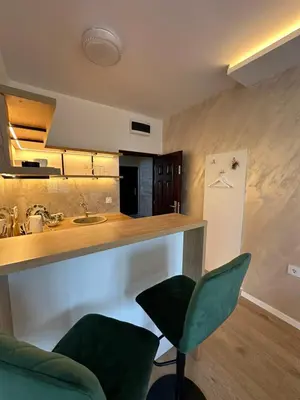 a kitchen with a counter and two green chairs at Apartman Igor in Surčin