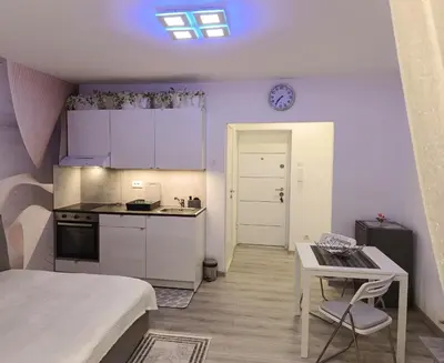 a kitchen with white cabinets and a table in a room at Studio Lara in Voždovac