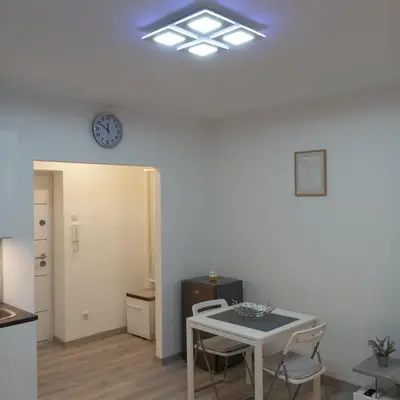 a dining room with a table and a clock on the wall at Studio Lara in Voždovac