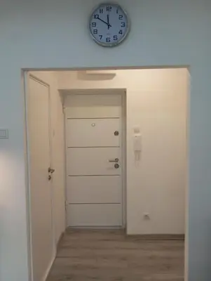 a clock on the wall above a white door at Studio Lara in Voždovac