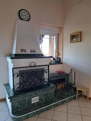 a fireplace in a living room with a clock on the wall at Ramonda house in Brestovik