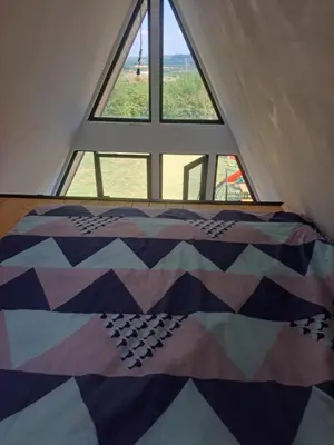 a quilt on a bed in front of a window at Vikendica na Avali in Donja Ralja