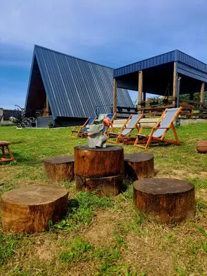 a group of logs with tables and chairs on a field at Vikendica na Avali in Donja Ralja