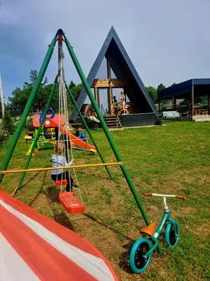 a child is sitting on a swing in a playground at Vikendica na Avali in Donja Ralja