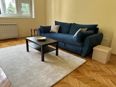 a living room with a blue couch and a table at petrov apartman in Belgrade