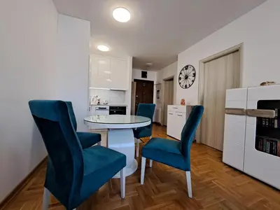 a kitchen with a table and blue chairs in a room at Plavi Paun Apartman in Belgrade
